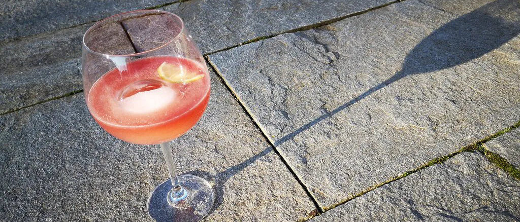 Weinglas gefüllt mit rot schimmerndem Longdrink