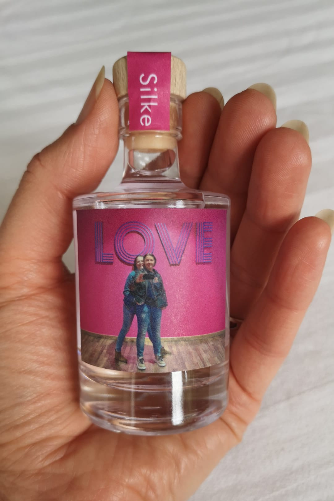 Personalisiertes Gastgeschenk zur Hochzeit: 50ml Spirituosen-Mini mit elegantem, schlichtem Etikett auf einer festlichen Tafel.